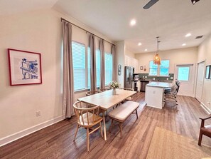 A modern kitchen with a central island, a dining area with a wooden table and chairs, and a small island with seating.