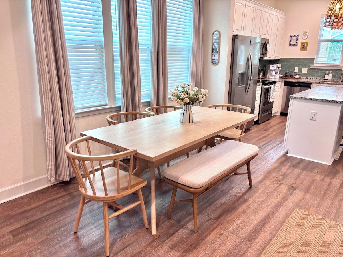 A modern kitchen with a dining area, wooden flooring, and a bench.