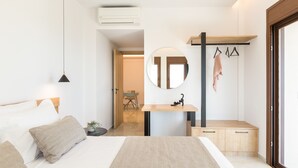 A modern bedroom with a large bed, a bedside table, a mirror, and a wooden bench. - Villa Santa Irini 2 - With Heated Pool (Agia Eirini)