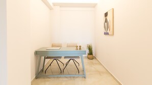 A dining area with a table and chairs, a potted plant, and a painting on the wall. - Villa Santa Irini 2 - With Heated Pool (Agia Eirini)