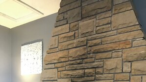 A stone fireplace with a metal screen, a blue bucket labeled "COAL", and a patterned rug. - Rustic barn Cottage in a rural village with traditional open fireplace sleeps 5. (Cockermouth)