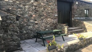 A stone building with a black door labeled "Lamb Garth." - Rustic barn Cottage in a rural village with traditional open fireplace sleeps 5. (Cockermouth)