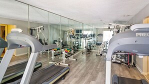 Un gimnàs amb cintes de córrer, aparells de musculació i un mirall gran.