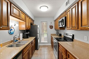 A kitchen with wooden cabinets, stainless steel appliances, a double sink, and a window with blinds.
