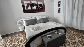 A neatly arranged bedroom with a bed, pillows, a bedside table, and a patterned carpet. - Ophelia's Dream: Caribbean sea in the vacation home one step away from Gallipoli (Tuglie)