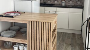 A compact kitchen with white cabinets, a wooden table, and a patterned backsplash. - Studio near La Rochelle (Dompierre-sur-Mer)