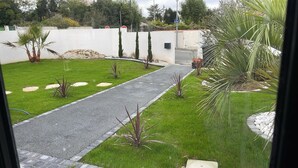 A pathway leading through a well-maintained garden with a variety of plants and a white wall in the background. - Studio near La Rochelle (Dompierre-sur-Mer)