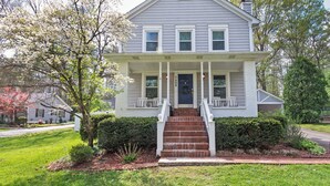 A two-story house with a front porch, a brick staircase, and a front yard.