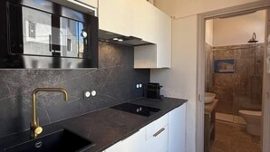 A modern kitchen with a black countertop, white cabinets, and a gold faucet. - To complete (Nîmes)