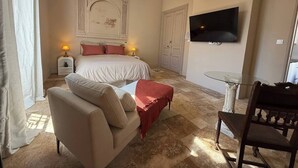 A bedroom with a bed, a sofa, a glass table, and a TV. - To complete (Nîmes)