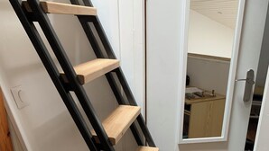 A wooden staircase with black railings leading to a room with a white door and a small window. - Maisonnette, in the middle of the pines, 5 mn walk to the beach, near Hossegor (Seignosse)