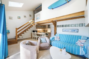 Un interior acogedor con una escalera, un comedor y una sala de estar con un sofá y una mesa de centro.