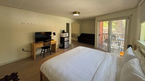 A bedroom with a bed, a desk with a TV, a microwave, and a sofa. - Non-Smoking King/Queen With Balcony - NKQB (Manitou Springs)