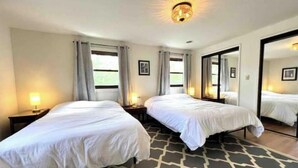 Ein Hotelzimmer mit zwei Betten, einem gemusterten Teppich und einer Kandelaber.