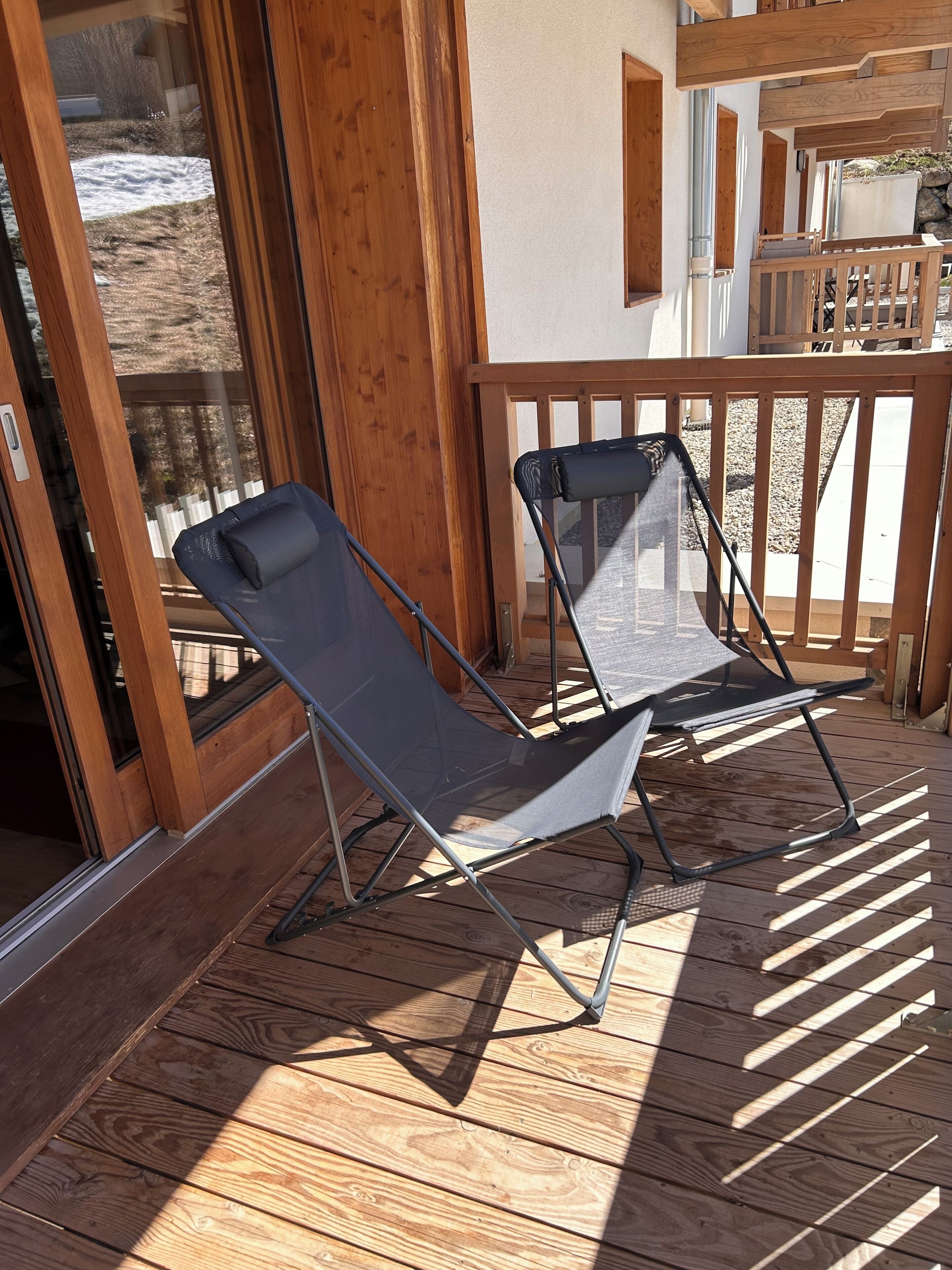 Une terrasse en bois avec deux chaises longues et une rambarde en bois.