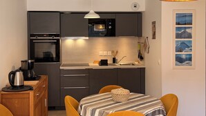 Une cuisine compacte dotée d’appareils électroménagers modernes, une table à manger avec des chaises et un luminaire au design original.
