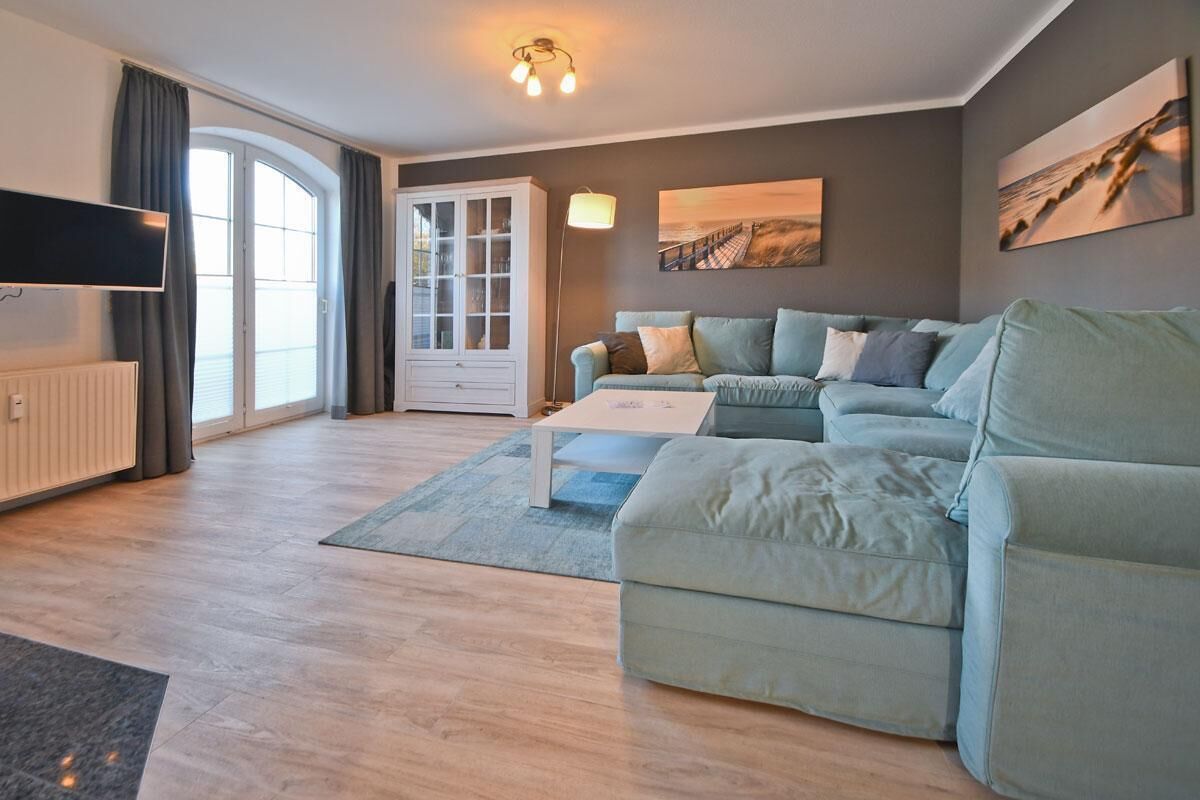 A modern living room with a sofa, a coffee table, a cabinet, and a flat-screen TV.