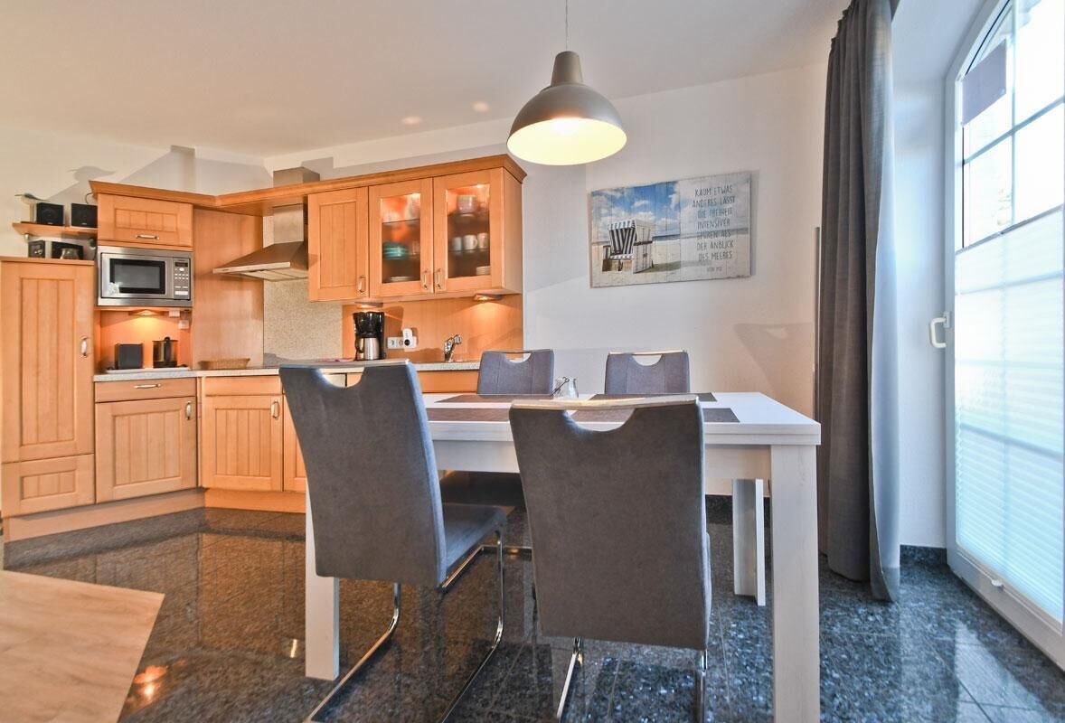Una cucina moderna con mobili in legno, forno a microonde integrato e zona pranzo con due sedie.