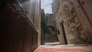 A narrow alleyway with a wooden door on the left and a stone wall on the right. - Pied-à-terre de Saint-Paul | Free public parking (Saint-Paul-de-Vence)