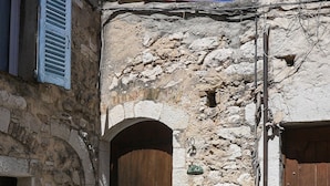 A stone building with a wooden door, a small staircase, and a sign indicating the number 10. - Pied-à-terre de Saint-Paul | Free public parking (Saint-Paul-de-Vence)