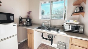 A compact kitchen with a microwave, coffee maker, toaster, and sink.