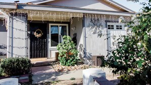 A house with a front porch decorated with string lights and a small tree.