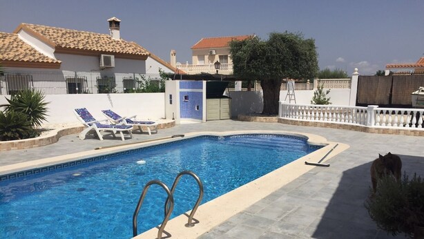 A swimming pool with two lounge chairs and a small covered area. - Beautiful, fully equipped detached villa with a private swimming pool. (Zurgena)