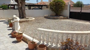A rooftop terrace with potted plants, a white balustrade, and a view of a residential area with houses and a gate. - Beautiful, fully equipped detached villa with a private swimming pool. (Zurgena)