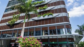 Um edifício moderno de vários andares, com varandas, grandes janelas e uma entrada destacada com um letreiro.