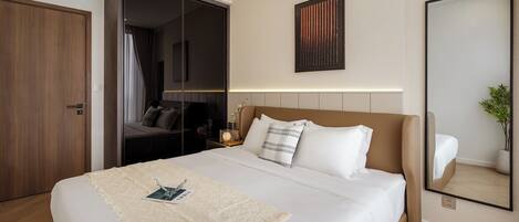 A modern hotel room with a large bed, a bedside table, a mirror, and a wardrobe.