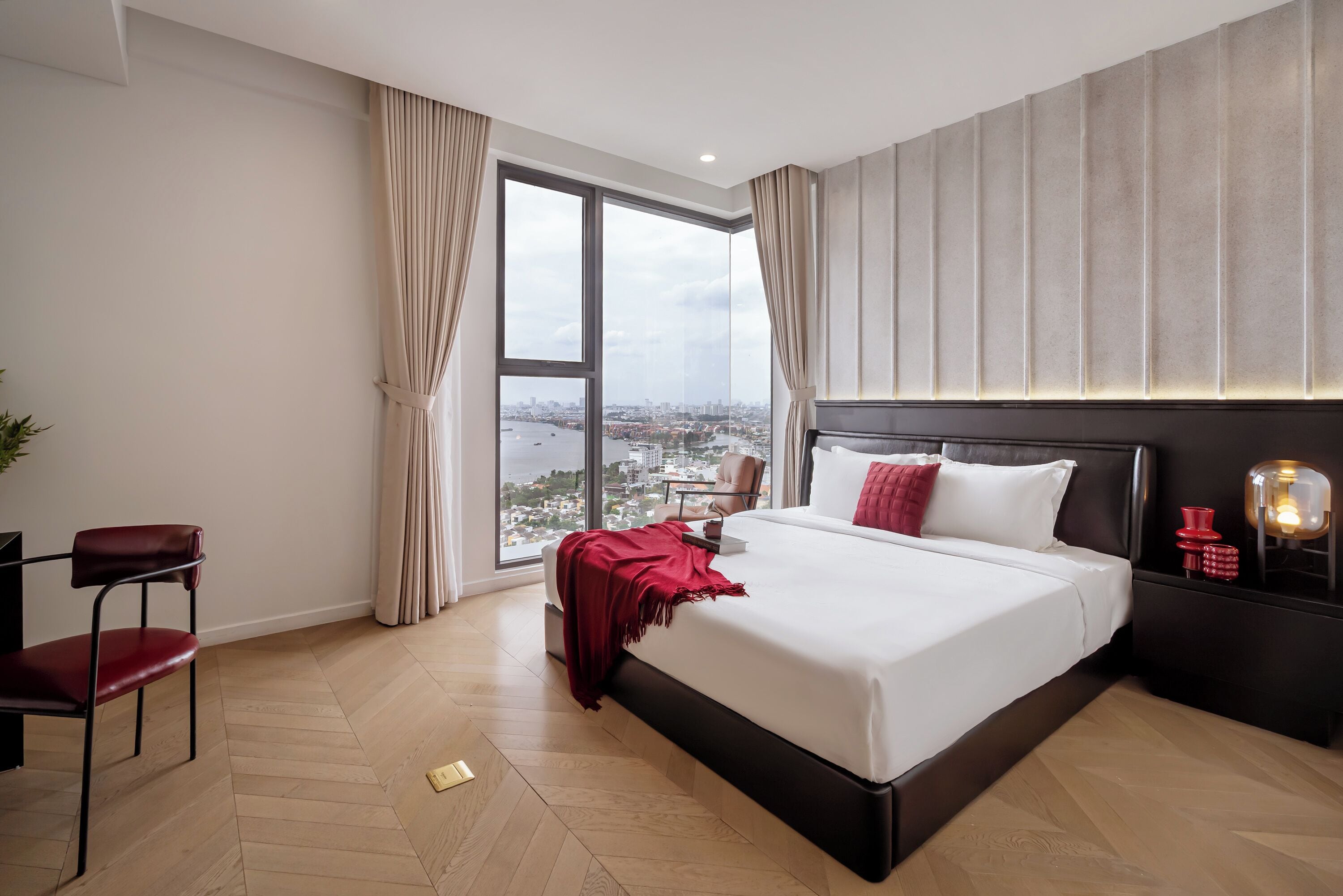 Une chambre d’hôtel moderne dotée d’un grand lit, d’un bureau avec une chaise et offrant une vue sur le paysage urbain grâce à une grande fenêtre.