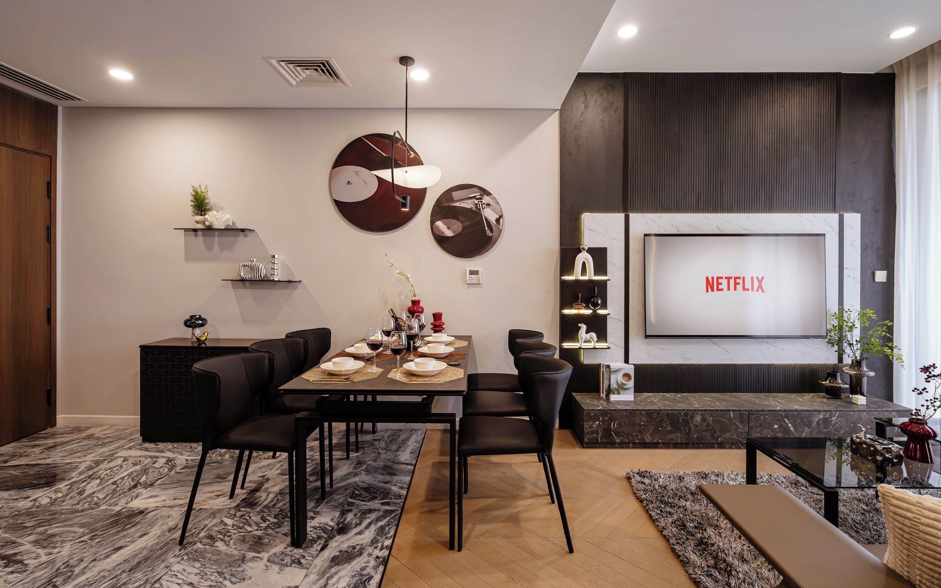 Uma sala de estar moderna com área de jantar, uma TV exibindo 'NETFLIX' e uma lareira.