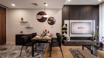 Uma sala de estar moderna com área de jantar, uma TV exibindo 'NETFLIX' e uma lareira.