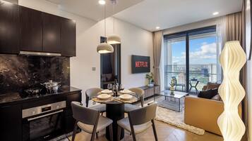 Una cucina moderna con mobili scuri, un piano di lavoro in marmo e un'area pranzo con un tavolo rotondo e sedie.