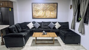 A modern living room with a sectional sofa, a wooden coffee table, and a large abstract painting on the wall.