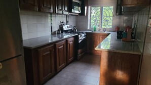 Una cucina con mobili in legno, un frigorifero in acciaio inossidabile, un forno a microonde, un fornello e un lavello.
