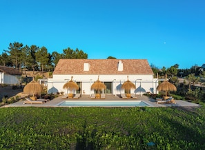 A villa with a swimming pool, outdoor seating, and a garden.