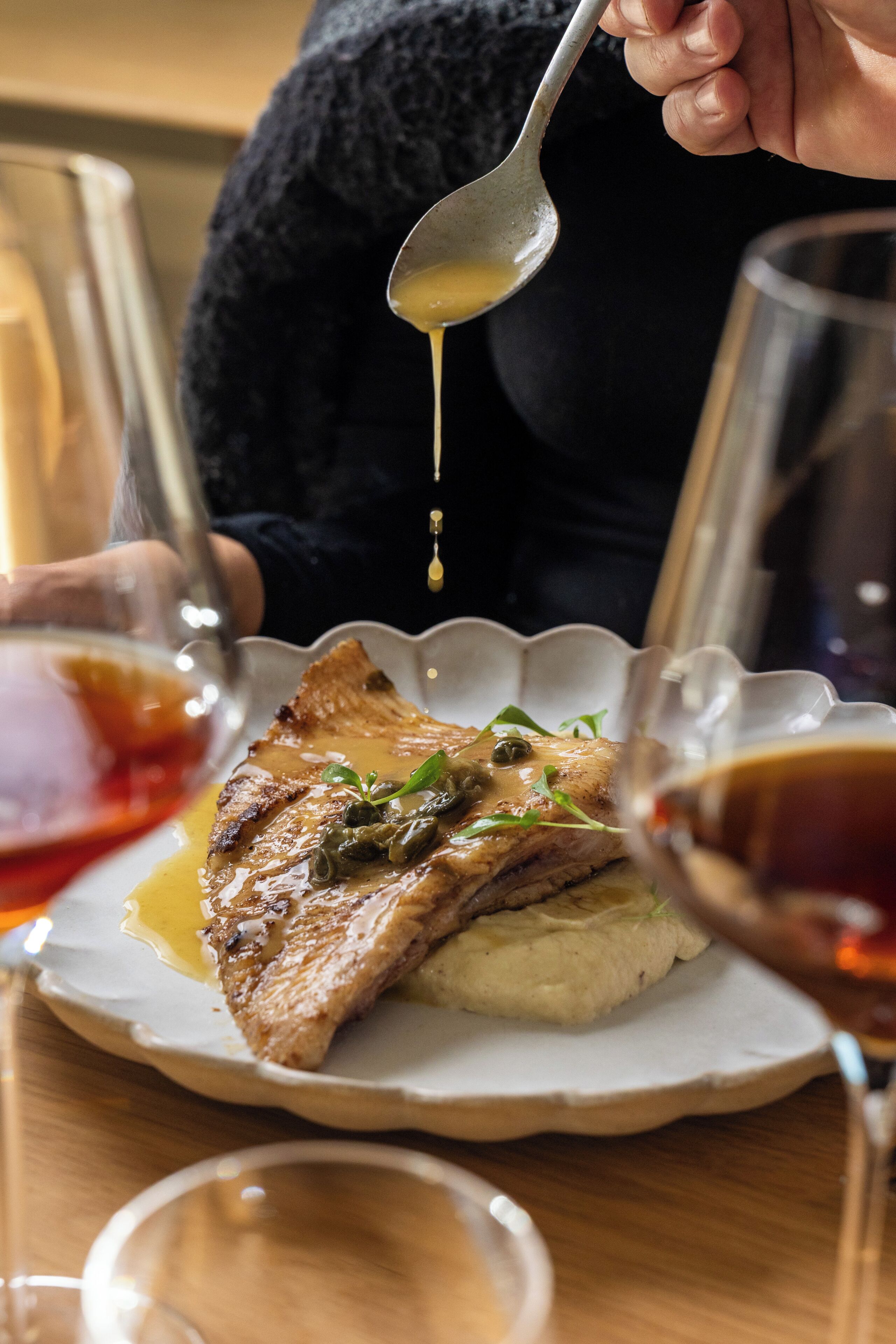Une personne qui verse de la sauce sur une assiette de nourriture.