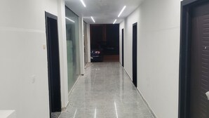 A corridor with a shiny tiled floor, white walls, and doors on both sides.