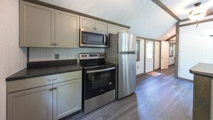 A modern kitchen with stainless steel appliances, light-colored cabinetry, and a wooden ceiling. - Tiny House w/Creek and Eagles (Millersburg)