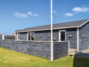 A modern building with a sloped roof, a fenced yard, and a clear sky.
