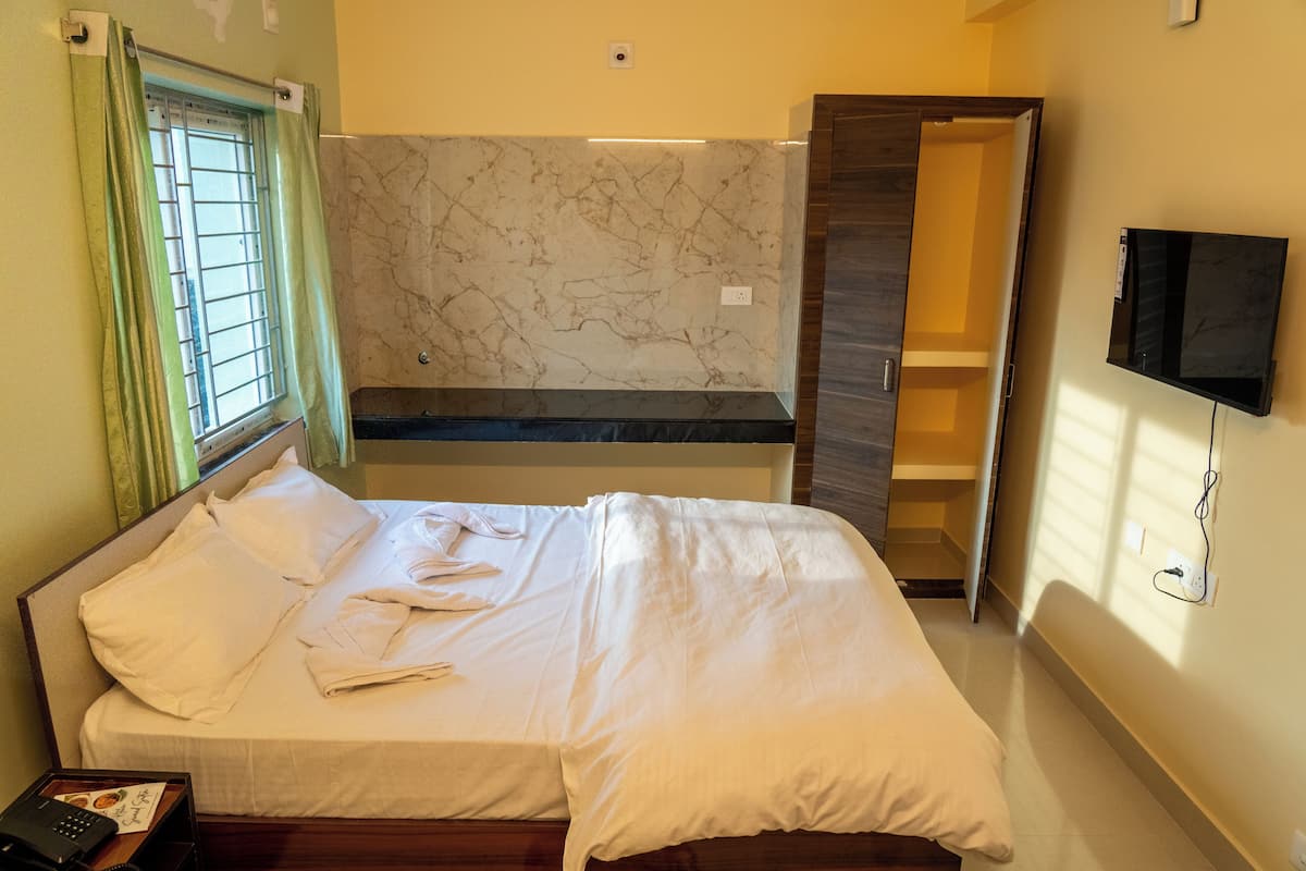 A hotel room with a bed, a TV, a bathroom, and a marble wall.