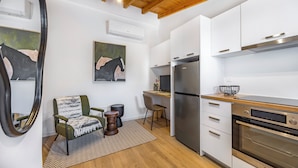 A modern kitchen with white cabinets, stainless steel appliances, and a wooden ceiling. - Olga Apt 4- Lovely Studio on Ground Floor (Limassol)