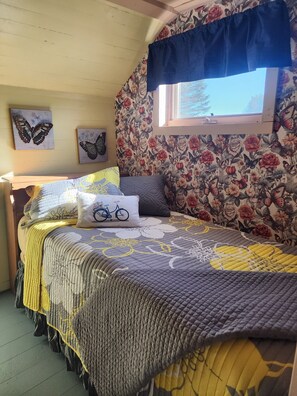 Una camera da letto con un letto, carta da parati a motivi floreali, opere d'arte a forma di farfalla e una finestra vista panoramica.