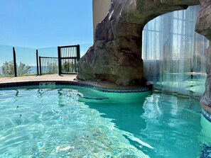 Une piscine aux eaux cristallines, agrémentée d’une formation rocheuse et séparée par une paroi de verre.