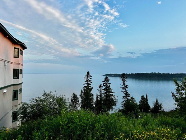 A building with a view of a calm lake and a distant island.