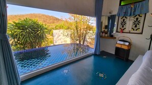 Ein Zimmer mit großem Fenster, Pool und Blick auf Grünflächen.