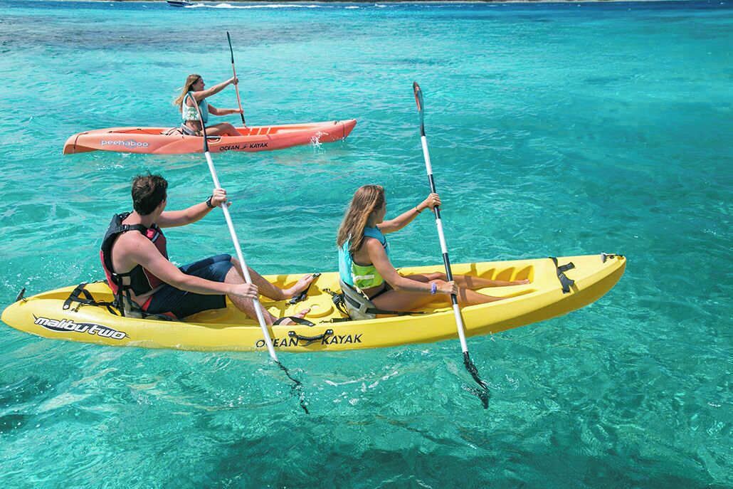 Two people kayaking on clear turquoise water.