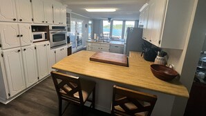 Une cuisine compacte avec des meubles blancs, un îlot central en bois et une vue sur l’extérieur.