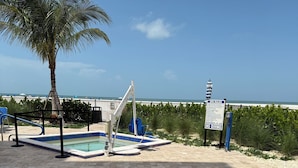 Zona de piscina con una palmera, una silla azul y un cartel que indica las normas del spa y la prohibición de buceo.